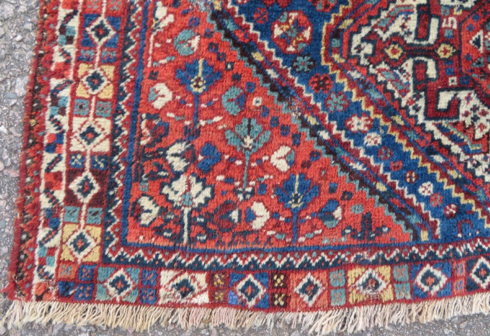 An antique South Persian Khamseh rug featuring three diamond-shaped central medallions and geometric bird motifs in shades of red, navy blue, and cream. View XI