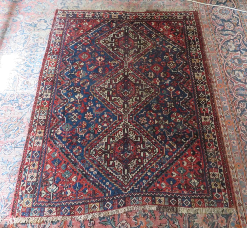An antique South Persian Khamseh rug featuring three diamond-shaped central medallions and geometric bird motifs in shades of red, navy blue, and cream. View XV