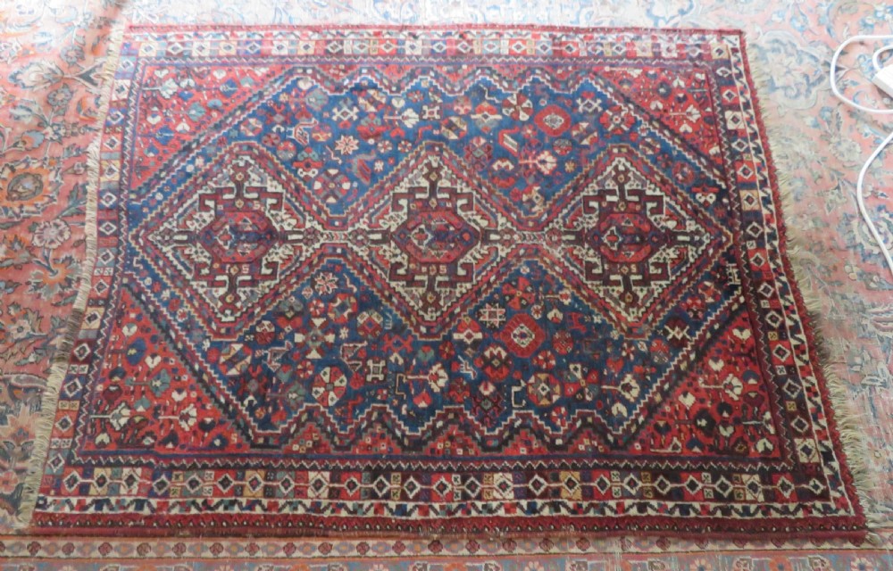 An antique South Persian Khamseh rug featuring three diamond-shaped central medallions and geometric bird motifs in shades of red, navy blue, and cream. View XVI