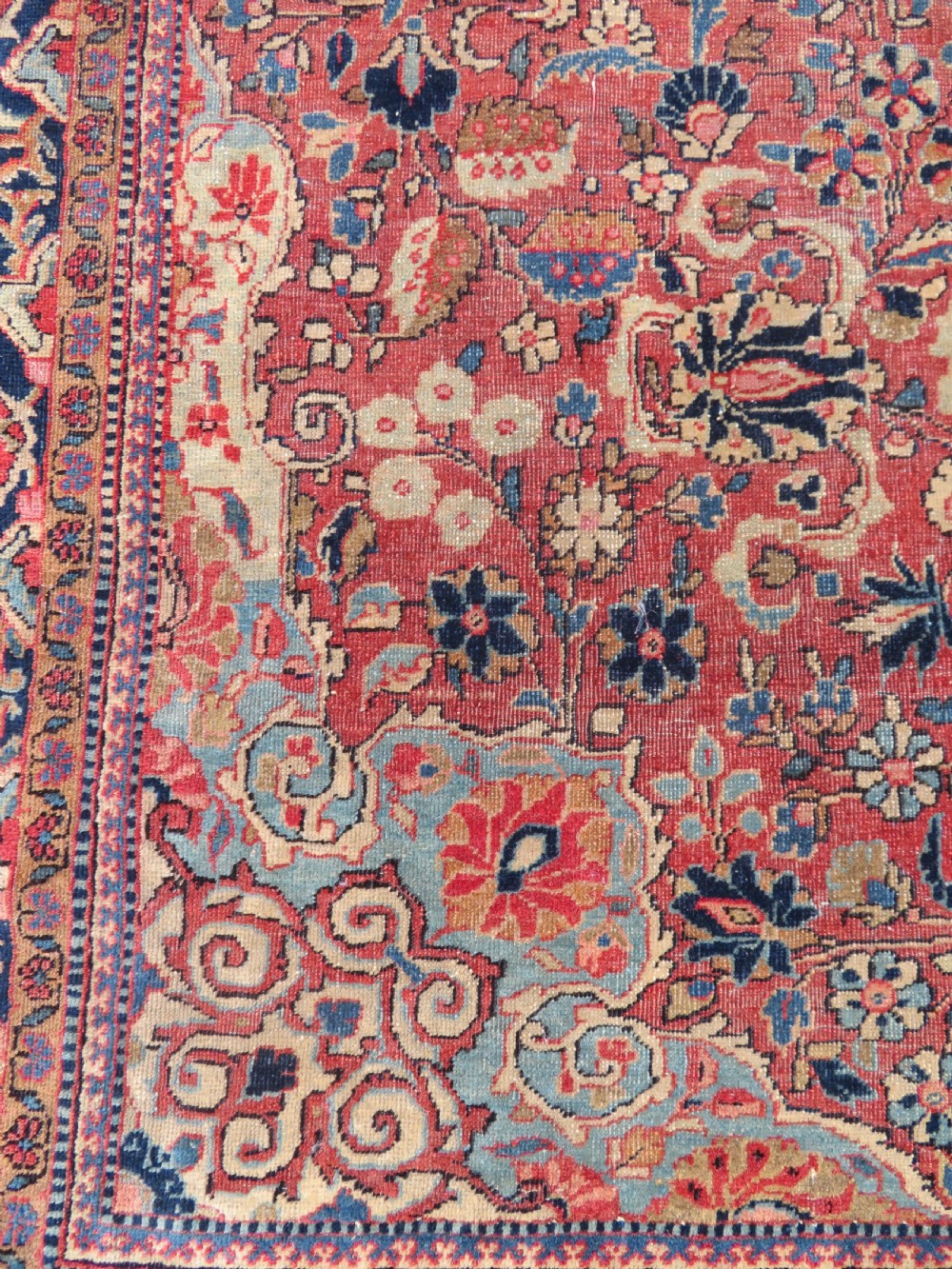 A rectangular hand-knotted wool Kashan rug featuring a central starburst medallion surrounded by dense floral patterns on a terracotta field with a navy border. View V