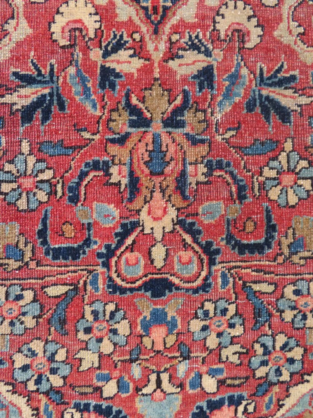 A rectangular hand-knotted wool Kashan rug featuring a central starburst medallion surrounded by dense floral patterns on a terracotta field with a navy border. View VI