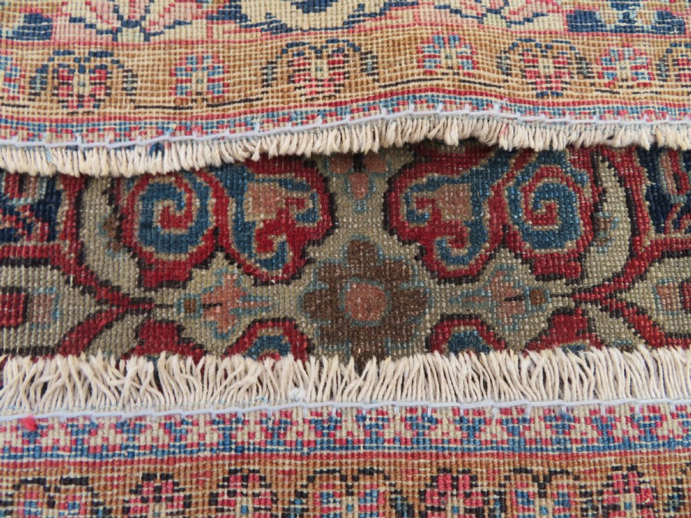 A rectangular hand-knotted wool Kashan rug featuring a central starburst medallion surrounded by dense floral patterns on a terracotta field with a navy border. View XIII