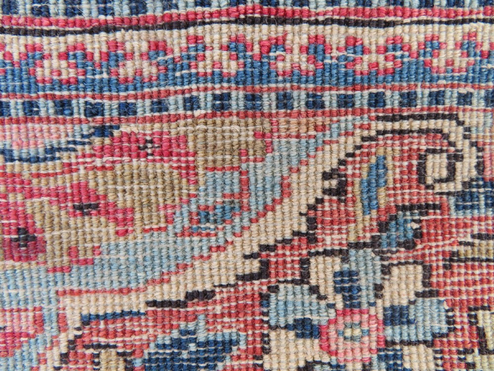 A rectangular hand-knotted wool Kashan rug featuring a central starburst medallion surrounded by dense floral patterns on a terracotta field with a navy border. View XIV