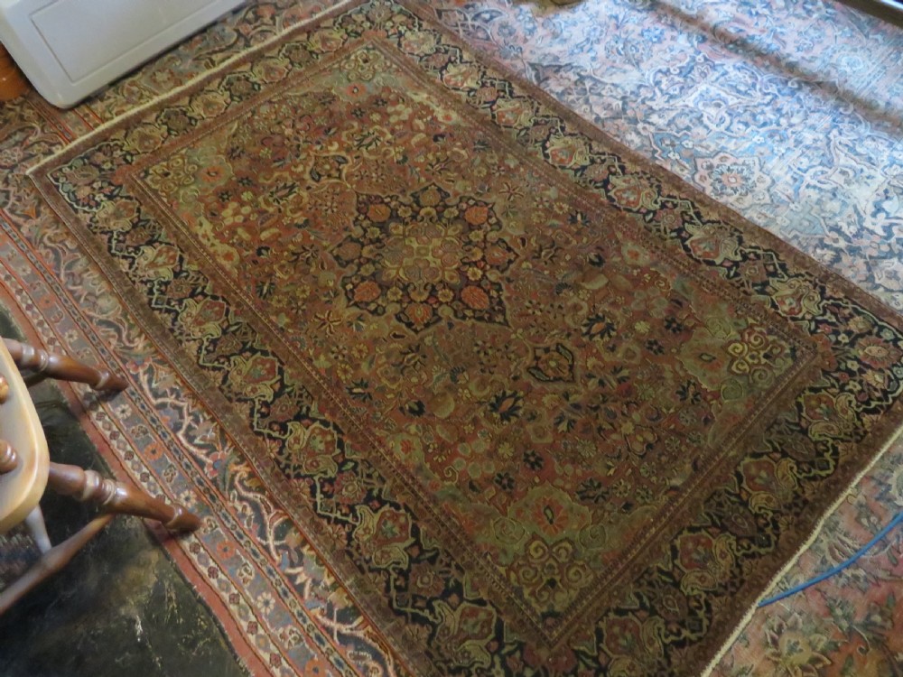A rectangular hand-knotted wool Kashan rug featuring a central starburst medallion surrounded by dense floral patterns on a terracotta field with a navy border. View XV