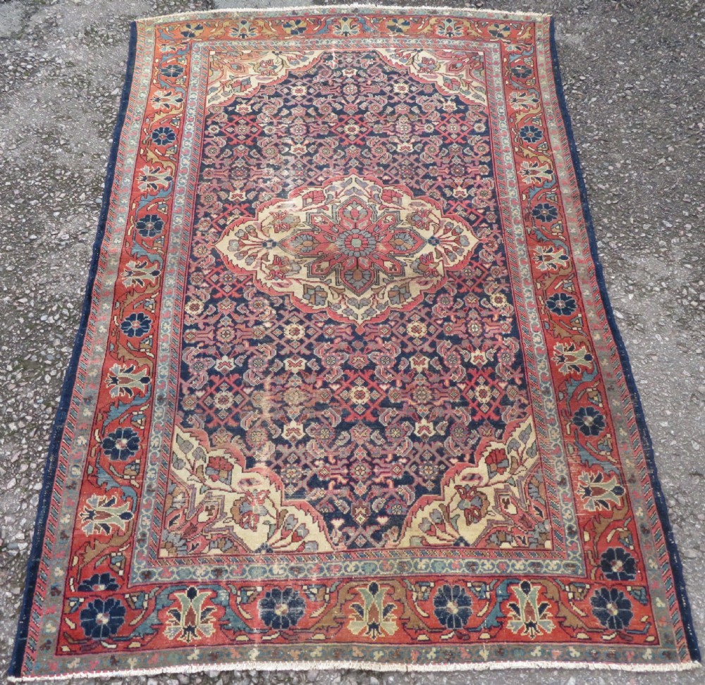 A rectangular antique Persian Malayer wool rug with a central cream and red medallion set against a dark navy field surrounded by intricate floral borders. View II