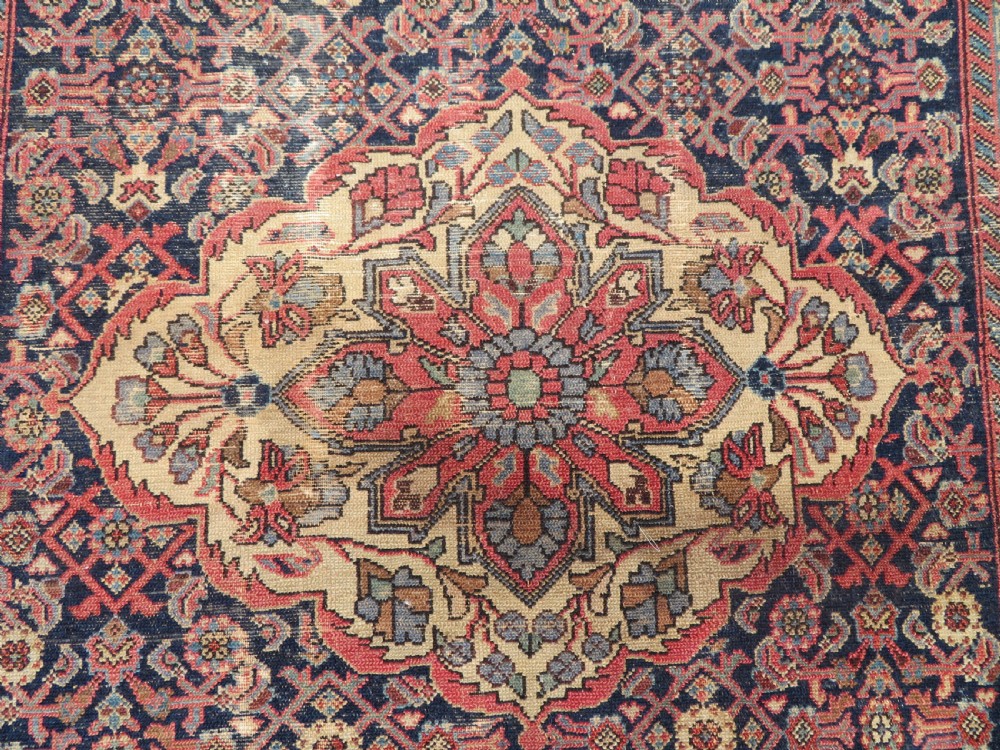 A rectangular antique Persian Malayer wool rug with a central cream and red medallion set against a dark navy field surrounded by intricate floral borders. View III