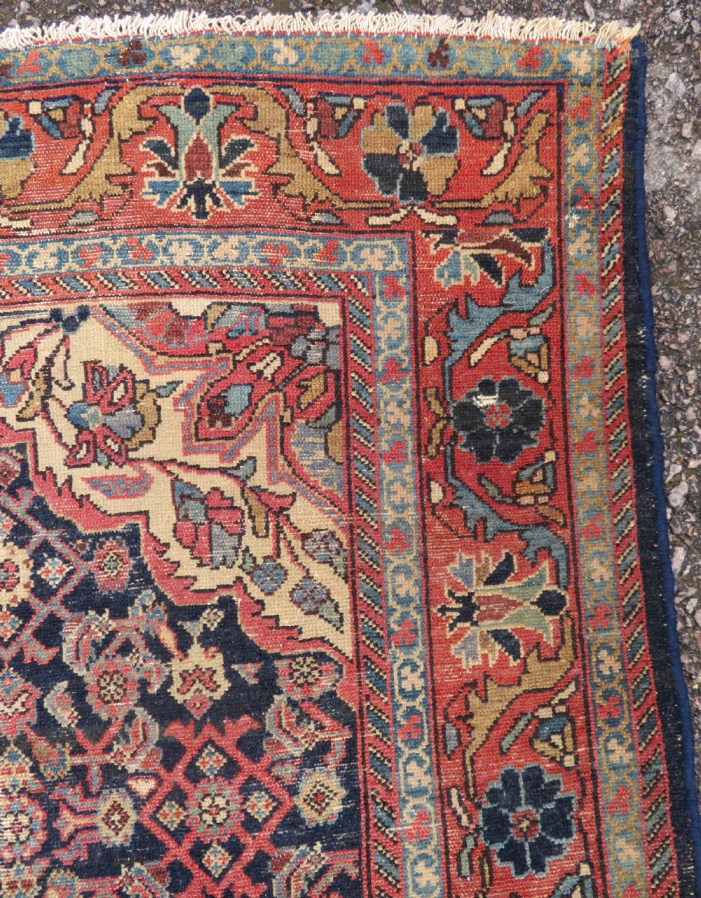 A rectangular antique Persian Malayer wool rug with a central cream and red medallion set against a dark navy field surrounded by intricate floral borders. View VII