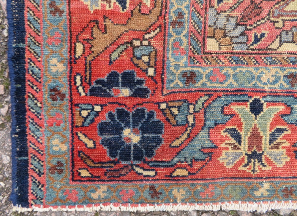 A rectangular antique Persian Malayer wool rug with a central cream and red medallion set against a dark navy field surrounded by intricate floral borders. View VIII