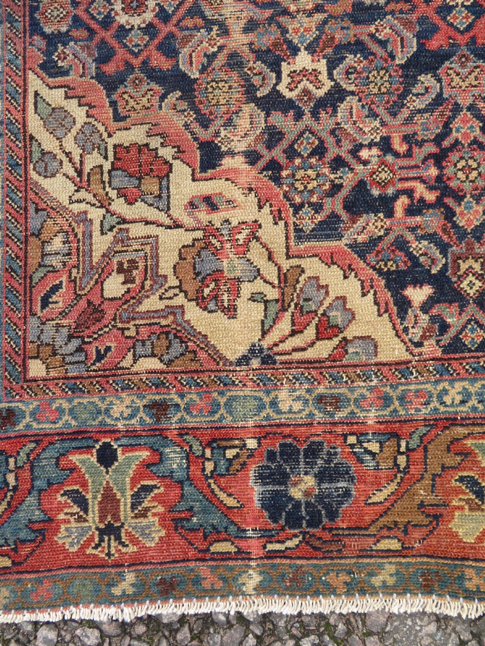 A rectangular antique Persian Malayer wool rug with a central cream and red medallion set against a dark navy field surrounded by intricate floral borders. View X