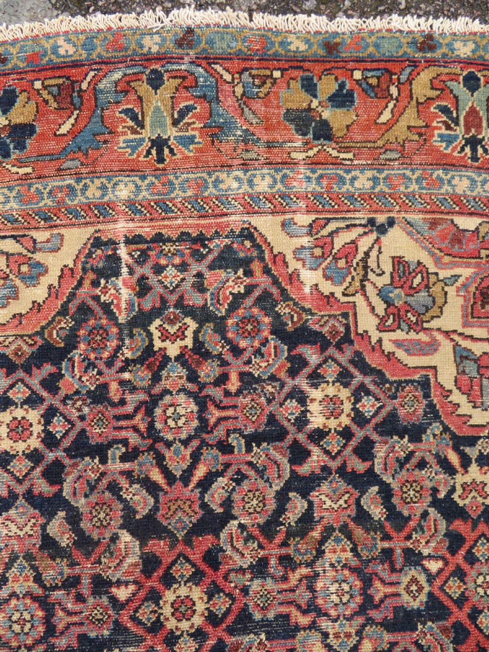A rectangular antique Persian Malayer wool rug with a central cream and red medallion set against a dark navy field surrounded by intricate floral borders. View XI
