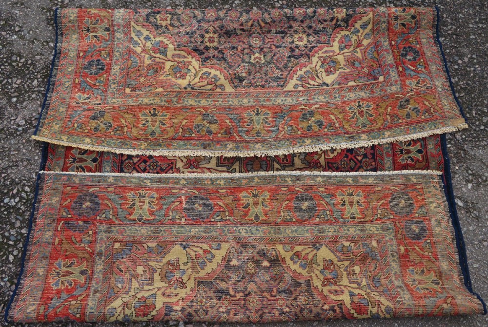 A rectangular antique Persian Malayer wool rug with a central cream and red medallion set against a dark navy field surrounded by intricate floral borders. View XII
