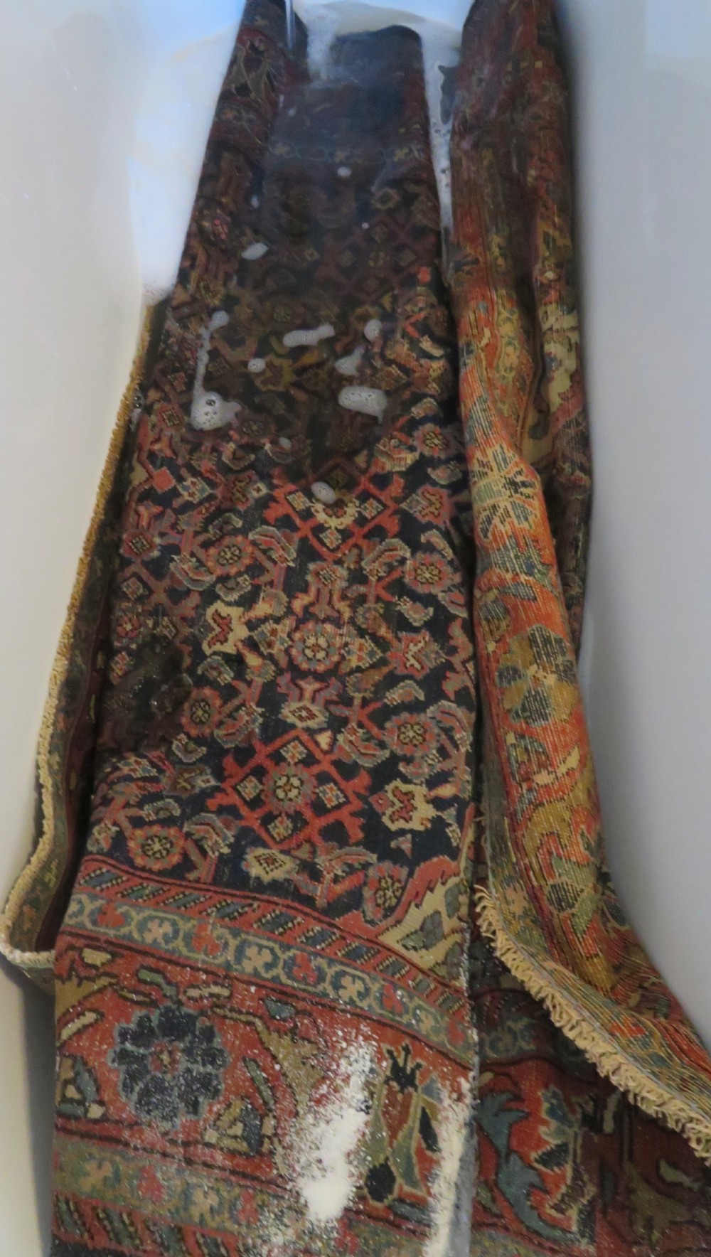 A rectangular antique Persian Malayer wool rug with a central cream and red medallion set against a dark navy field surrounded by intricate floral borders. View XIX
