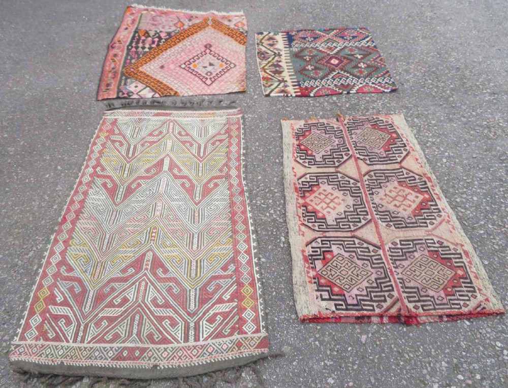 A group of four individual hand-woven Turkish kilim mats featuring vibrant geometric patterns, diamond medallions, and zig-zag borders. View II