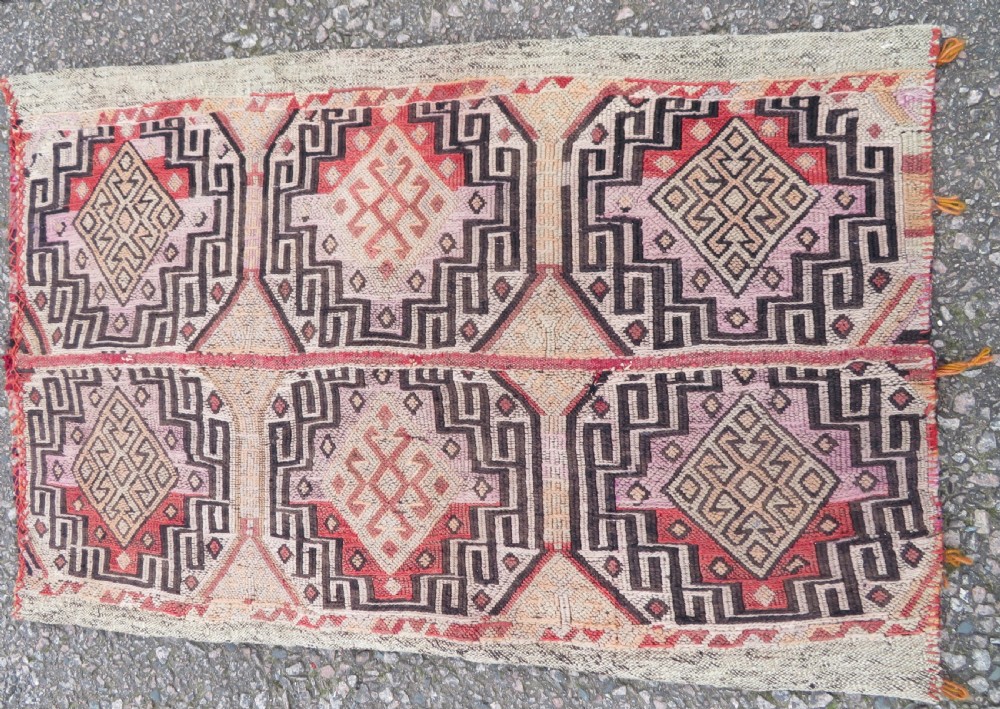 A group of four individual hand-woven Turkish kilim mats featuring vibrant geometric patterns, diamond medallions, and zig-zag borders. View III