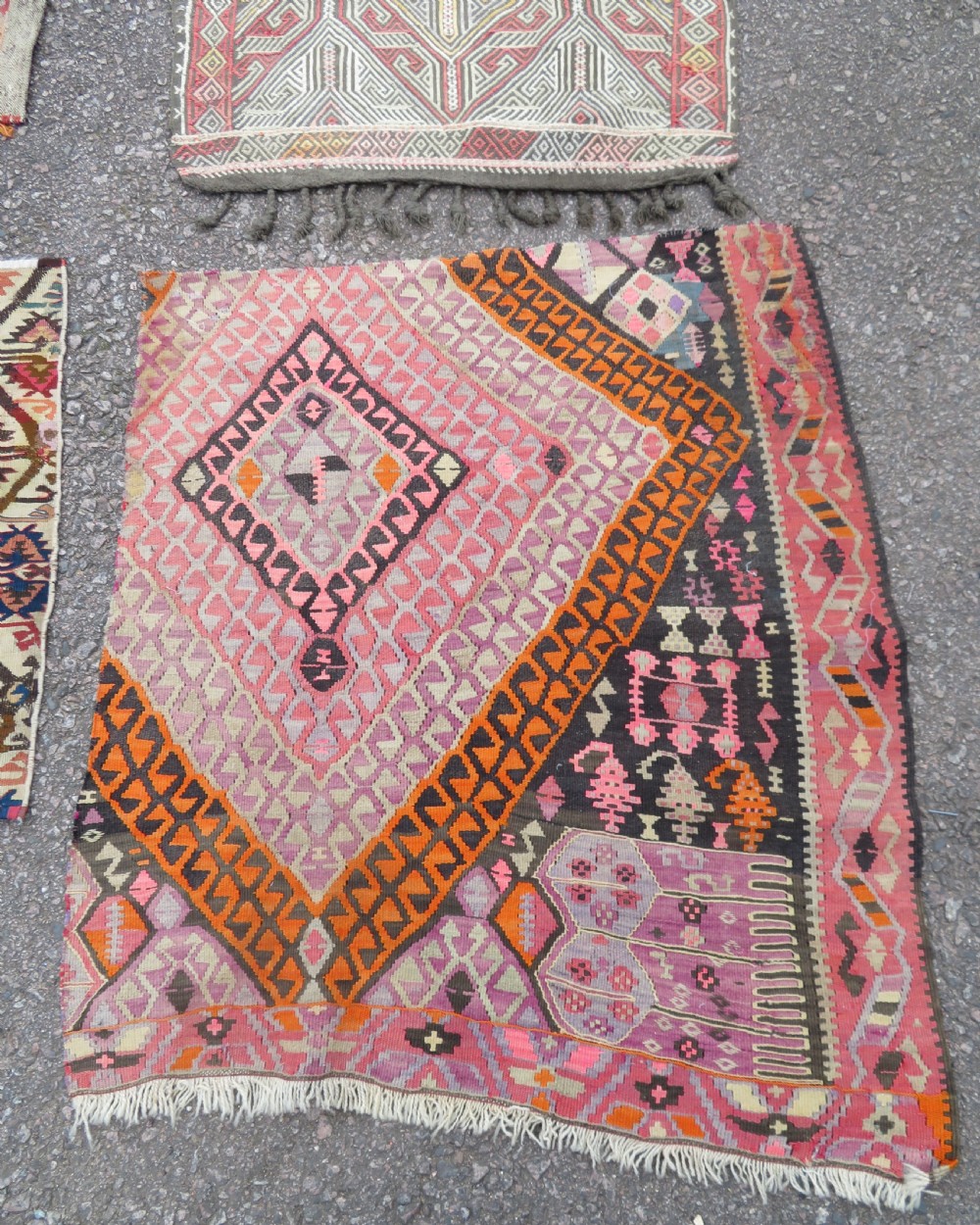 A group of four individual hand-woven Turkish kilim mats featuring vibrant geometric patterns, diamond medallions, and zig-zag borders. View VI
