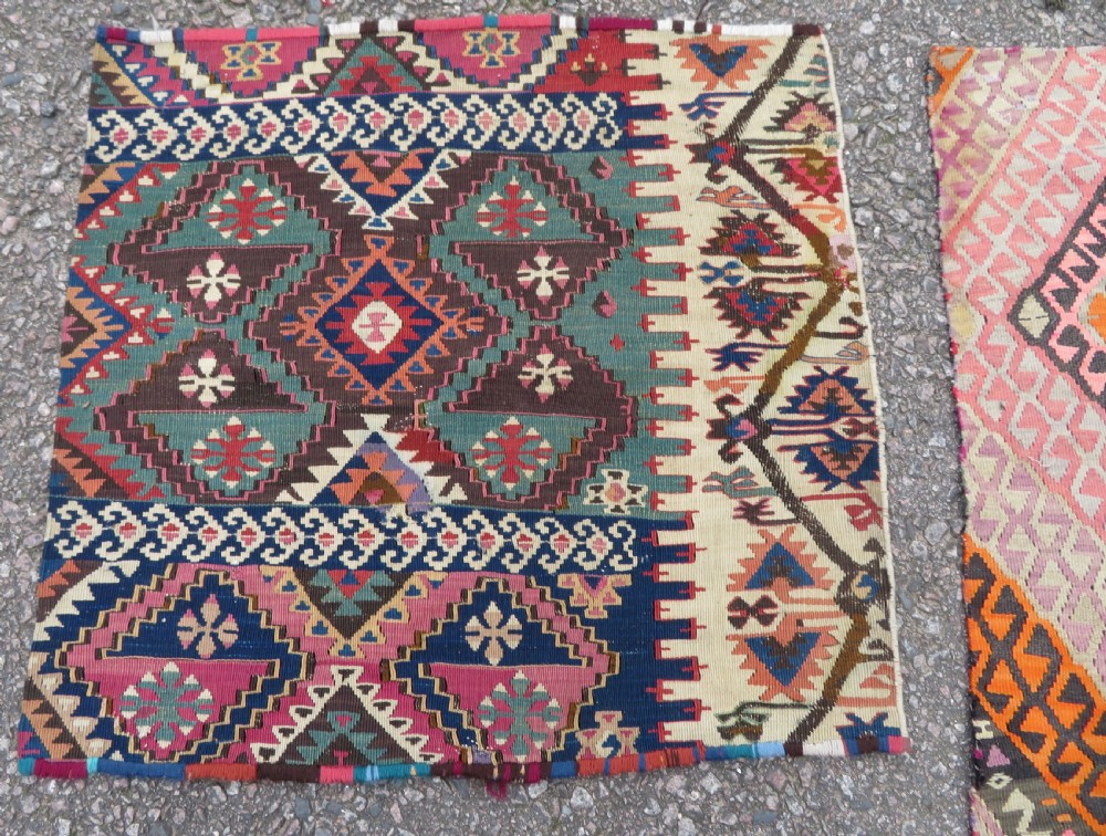 A group of four individual hand-woven Turkish kilim mats featuring vibrant geometric patterns, diamond medallions, and zig-zag borders. View VII
