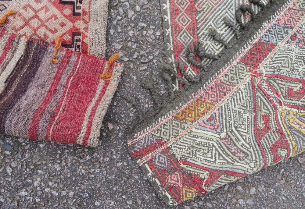 A group of four individual hand-woven Turkish kilim mats featuring vibrant geometric patterns, diamond medallions, and zig-zag borders. View IX