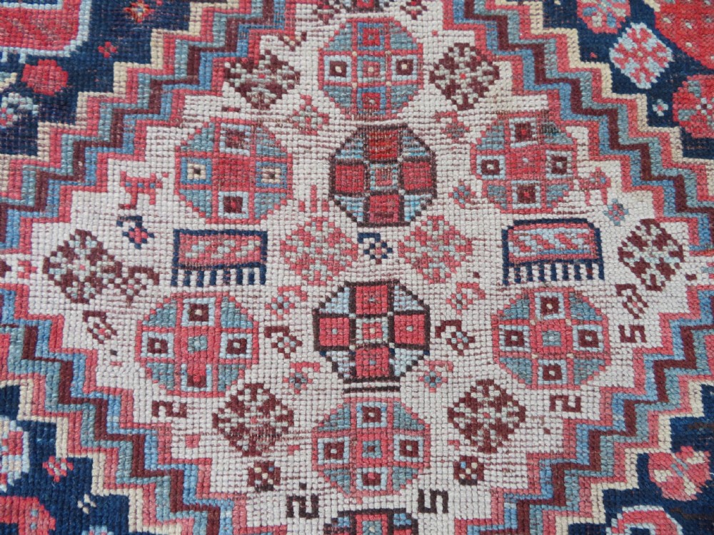 An antique hand-knotted Khamseh tribal wool rug featuring three geometric pole medallions in navy blue, terracotta red, and cream with detailed borders. View XVIII