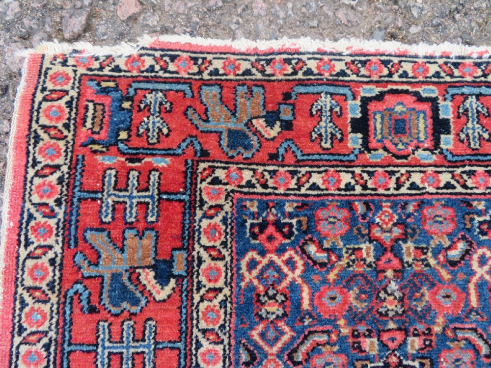 An antique West Persian Senneh wool rug featuring a navy blue stepped diamond medallion centered on a terracotta red field with intricate geometric borders. View VIII
