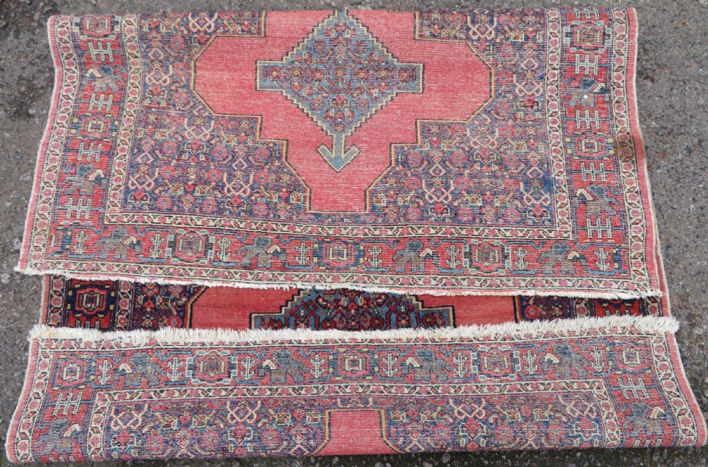 An antique West Persian Senneh wool rug featuring a navy blue stepped diamond medallion centered on a terracotta red field with intricate geometric borders. View XIII