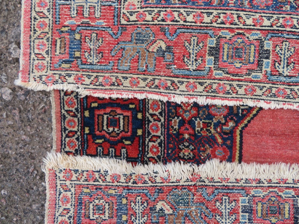 An antique West Persian Senneh wool rug featuring a navy blue stepped diamond medallion centered on a terracotta red field with intricate geometric borders. View XIV