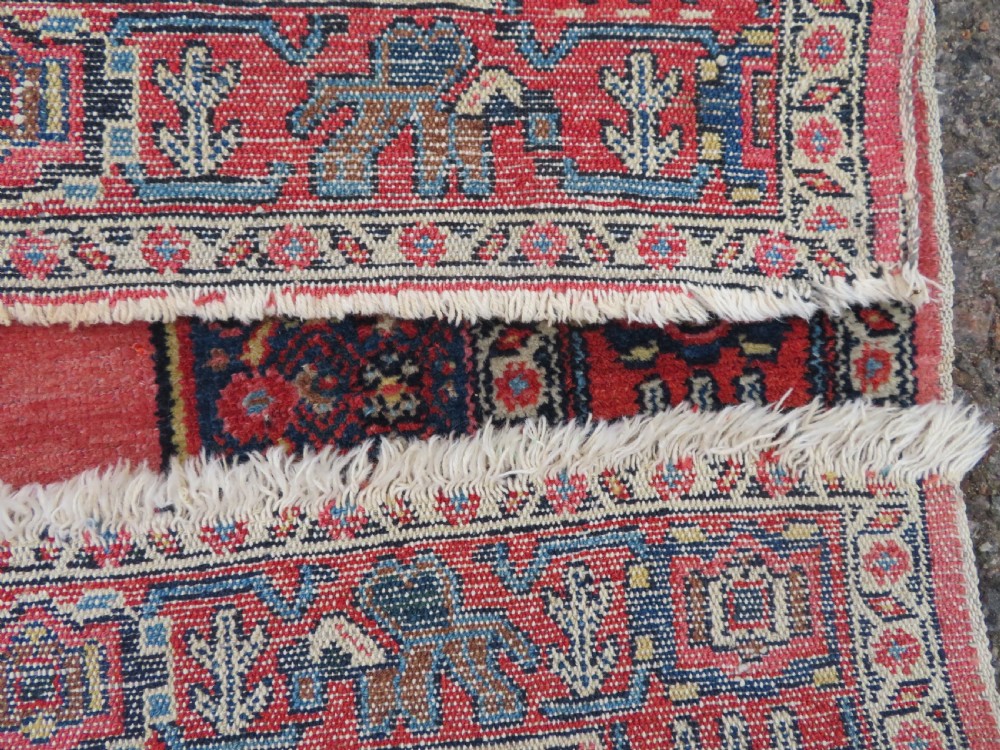 An antique West Persian Senneh wool rug featuring a navy blue stepped diamond medallion centered on a terracotta red field with intricate geometric borders. View XV