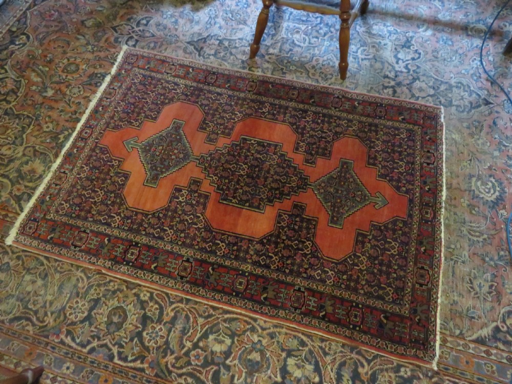 An antique West Persian Senneh wool rug featuring a navy blue stepped diamond medallion centered on a terracotta red field with intricate geometric borders. View XVIII