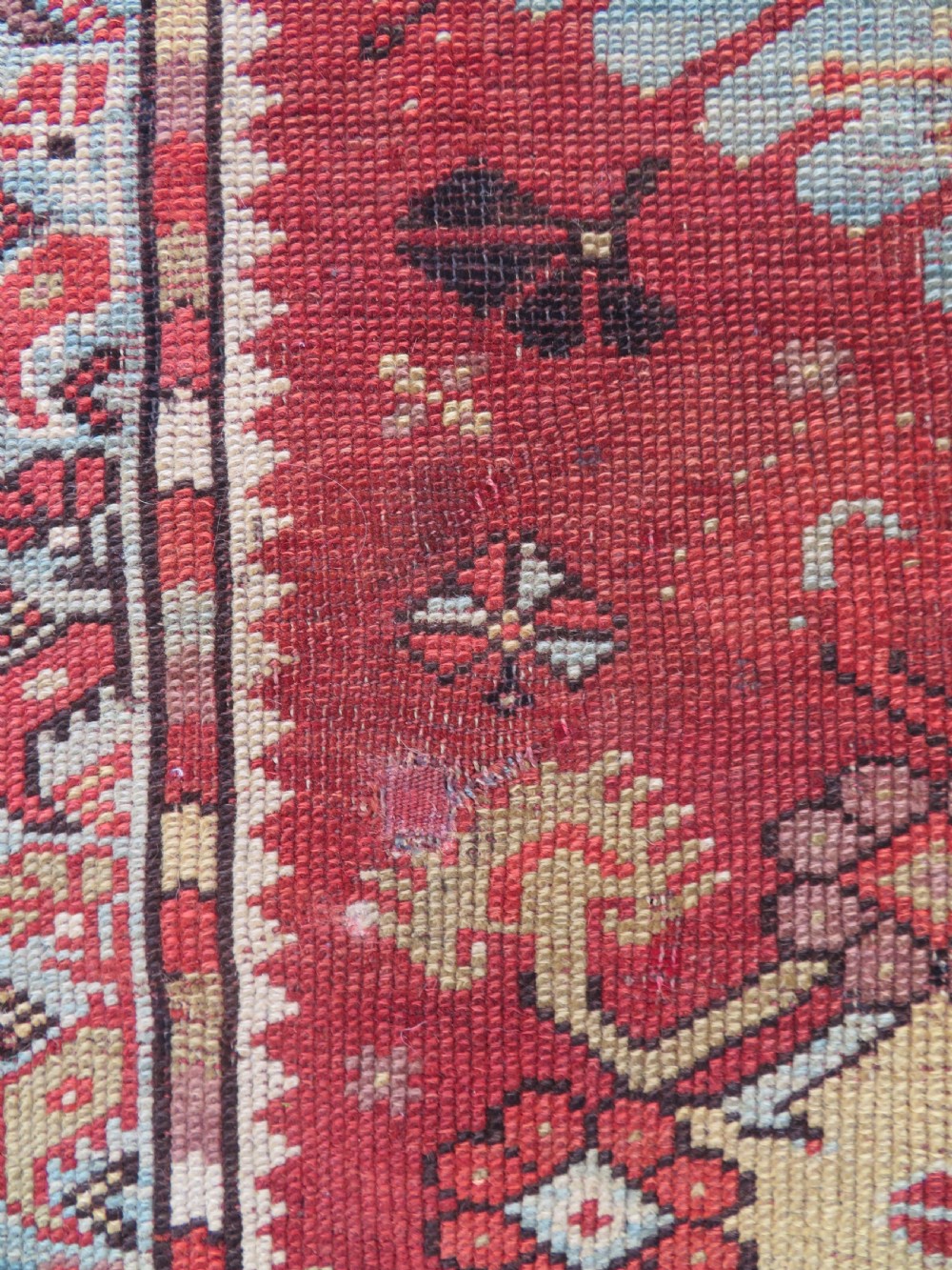 An antique handwoven Anatolian Ada Melas wool rug featuring central geometric medallions in grey, red, and ochre framed by detailed botanical borders. View VI