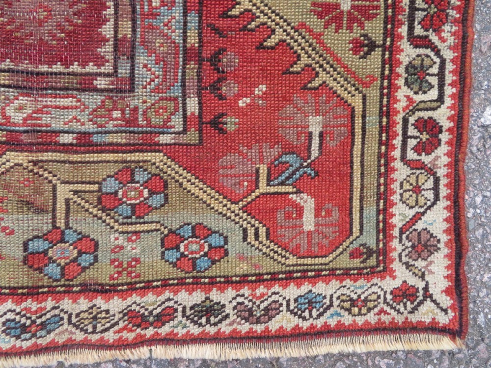 An antique handwoven Anatolian Ada Melas wool rug featuring central geometric medallions in grey, red, and ochre framed by detailed botanical borders. View XII