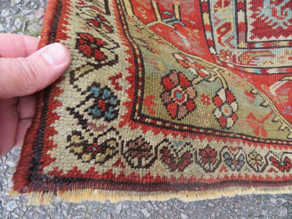 An antique handwoven Anatolian Ada Melas wool rug featuring central geometric medallions in grey, red, and ochre framed by detailed botanical borders. View XIII