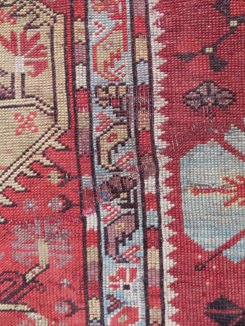An antique handwoven Anatolian Ada Melas wool rug featuring central geometric medallions in grey, red, and ochre framed by detailed botanical borders. View XIV