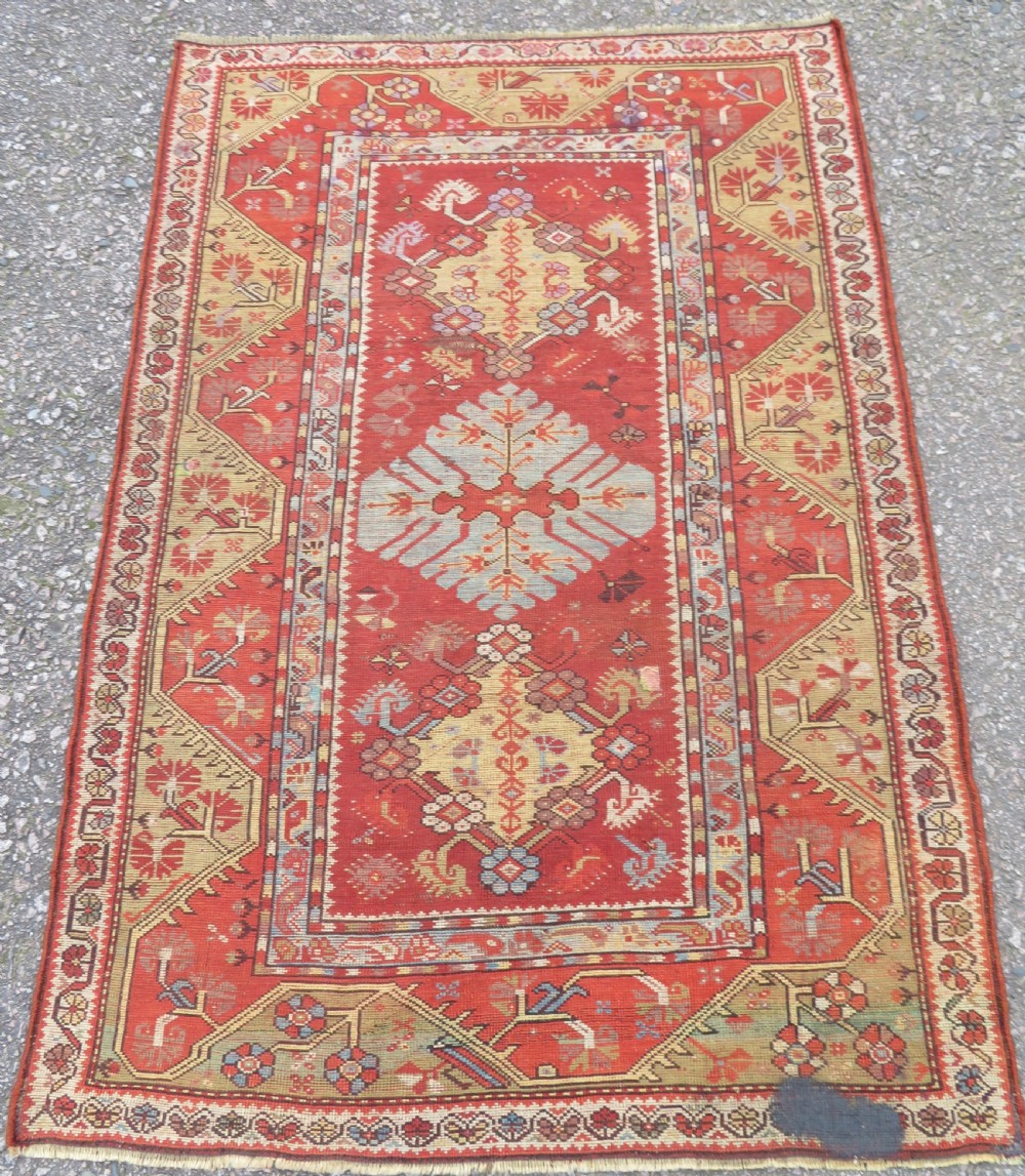 An antique handwoven Anatolian Ada Melas wool rug featuring central geometric medallions in grey, red, and ochre framed by detailed botanical borders. View XV