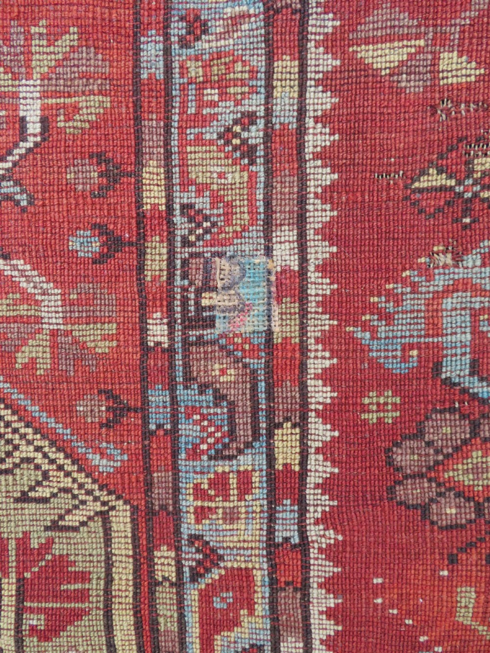 An antique handwoven Anatolian Ada Melas wool rug featuring central geometric medallions in grey, red, and ochre framed by detailed botanical borders. View XVIII