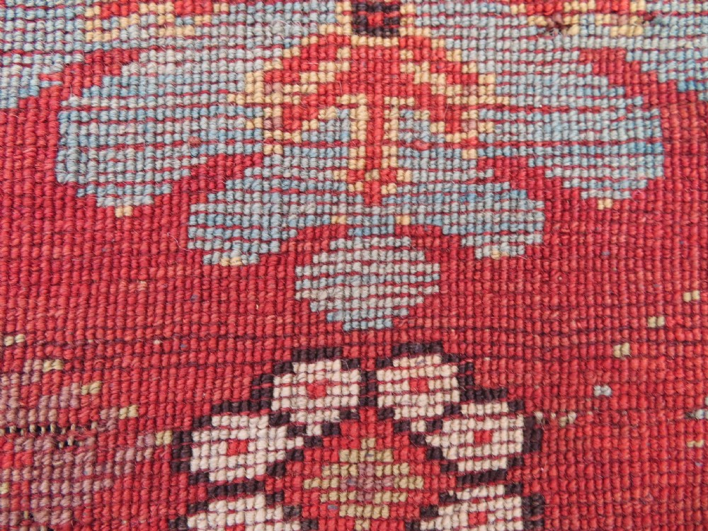 An antique handwoven Anatolian Ada Melas wool rug featuring central geometric medallions in grey, red, and ochre framed by detailed botanical borders. View XIX
