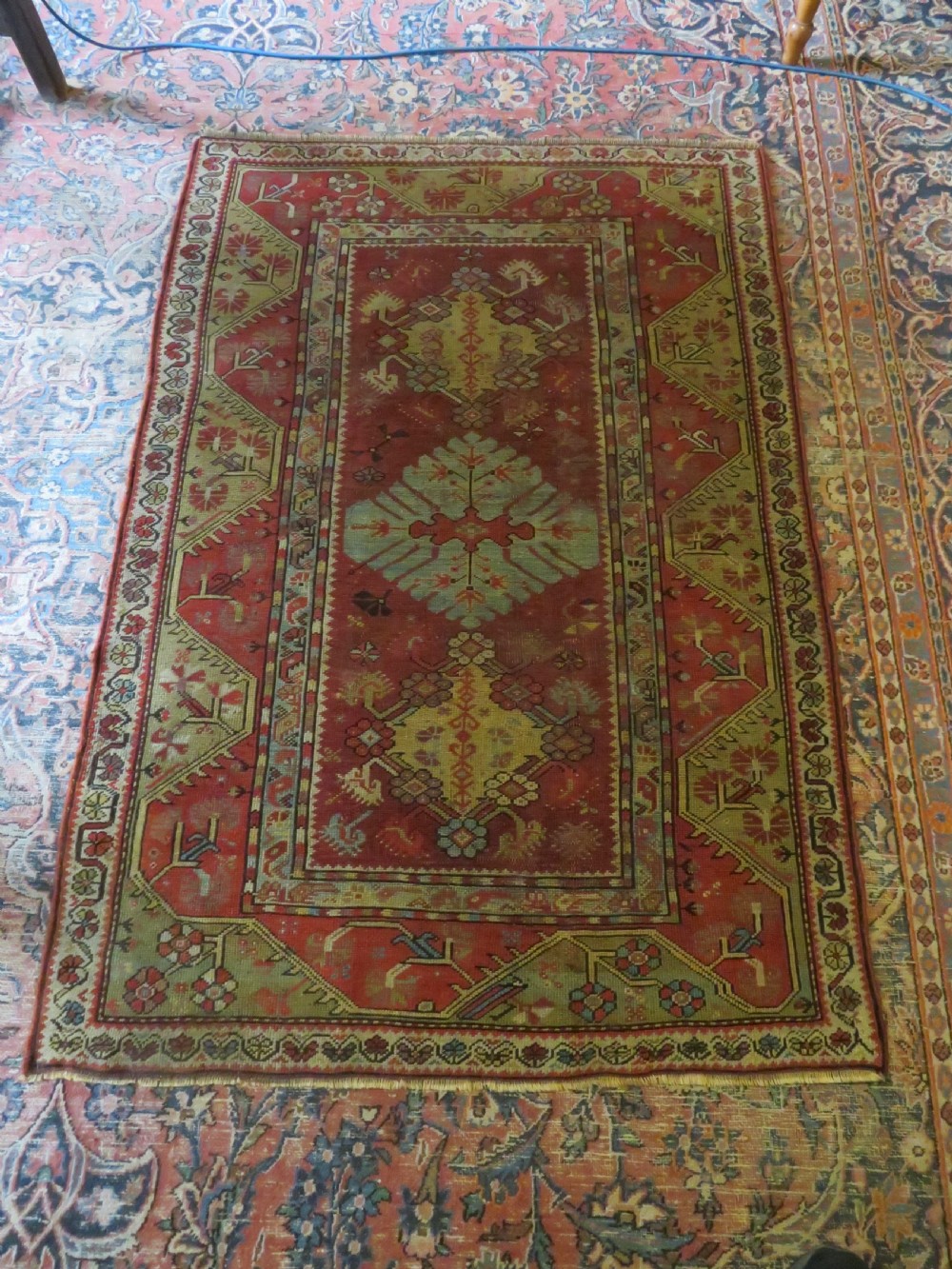 An antique handwoven Anatolian Ada Melas wool rug featuring central geometric medallions in grey, red, and ochre framed by detailed botanical borders. View XX