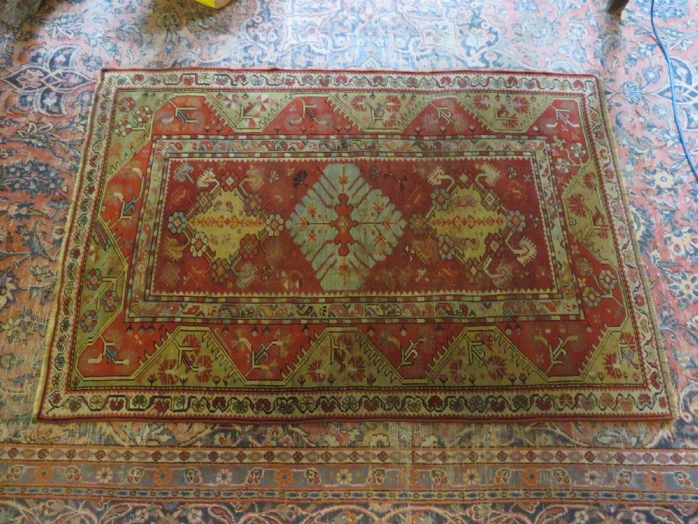 An antique handwoven Anatolian Ada Melas wool rug featuring central geometric medallions in grey, red, and ochre framed by detailed botanical borders. View XXI
