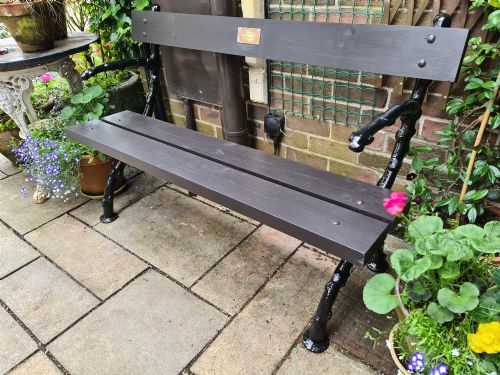 fig 1. A 19th-century cast-iron and wooden garden bench featuring rustic branch-form end frames and a dark-stained timber seat and backrest.