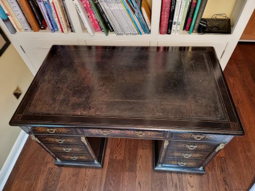 fig 1. A Victorian ebonised wooden pedestal desk with floral marquetry inlay, leather insert top, brass handles, and gilt corner mounts.