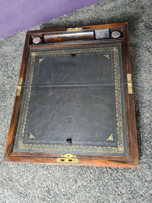 fig 1. A rectangular rosewood box featuring brass edge binding, inlaid brass stringing, a brass escutcheon, and a tassel key inserted in the lock.