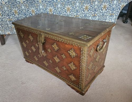 fig 1. An antique padouk wood Zanzibar chest decorated with geometric brass studs, pierced brass plaques, and heavy iron side handles.