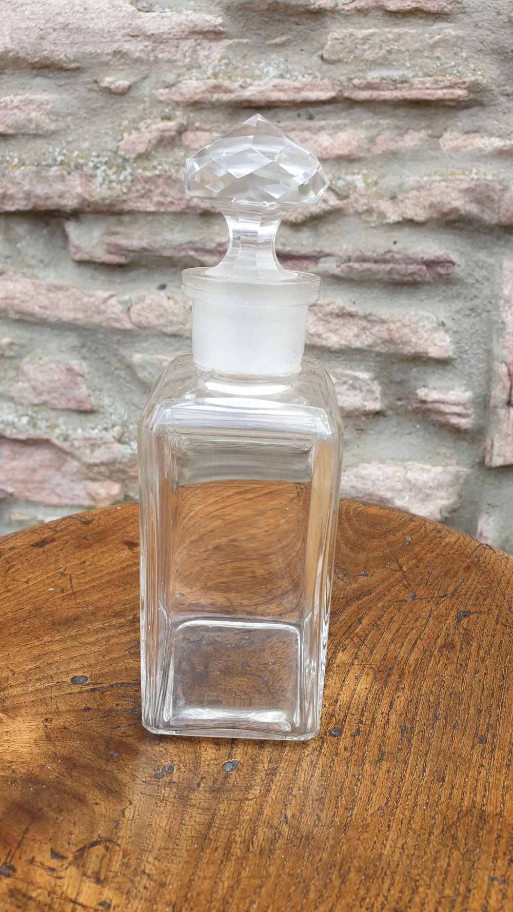 A clear glass rectangular perfume bottle with a faceted geometric stopper and an original circular paper label reading Potter and Moores Mitcham Lavender. View V