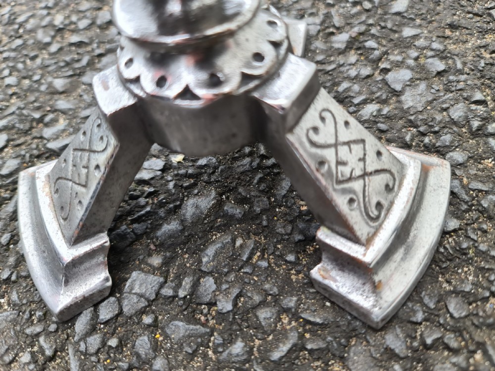 A pair of engraved steel fire dogs featuring urn-shaped tops, scroll side handles, geometric etchings, and tripod feet against a grey background. View VIII