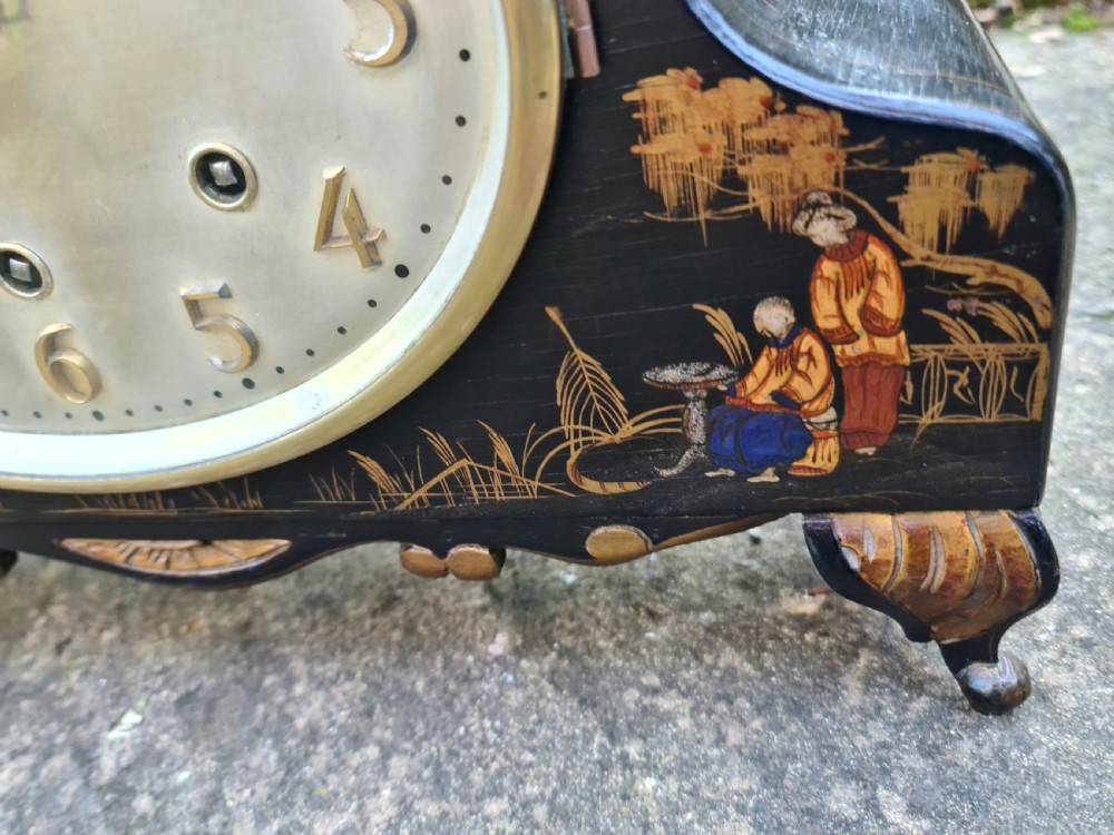 An antique black lacquered mantel clock decorated with gold chinoiserie scenes and an oval brass-rimmed clock face. View IV