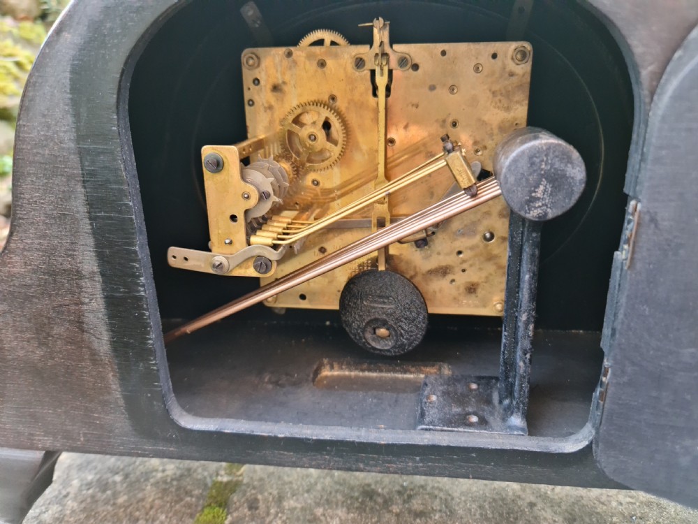 An antique black lacquered mantel clock decorated with gold chinoiserie scenes and an oval brass-rimmed clock face. View X