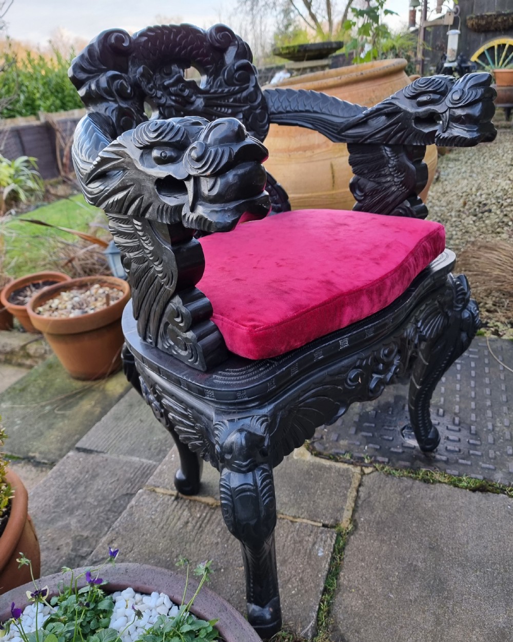 A dark carved hardwood armchair featuring carved dragon head armrests, an openwork backrest, cabriole legs, and a red velvet seat cushion. View IV