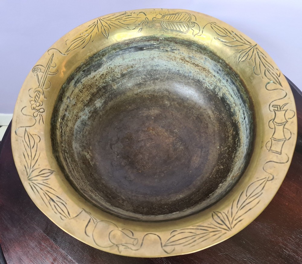 A large brass bowl featuring engraved dragon and cloud patterns with a flared rim, displayed on a dark carved wooden stand. View III