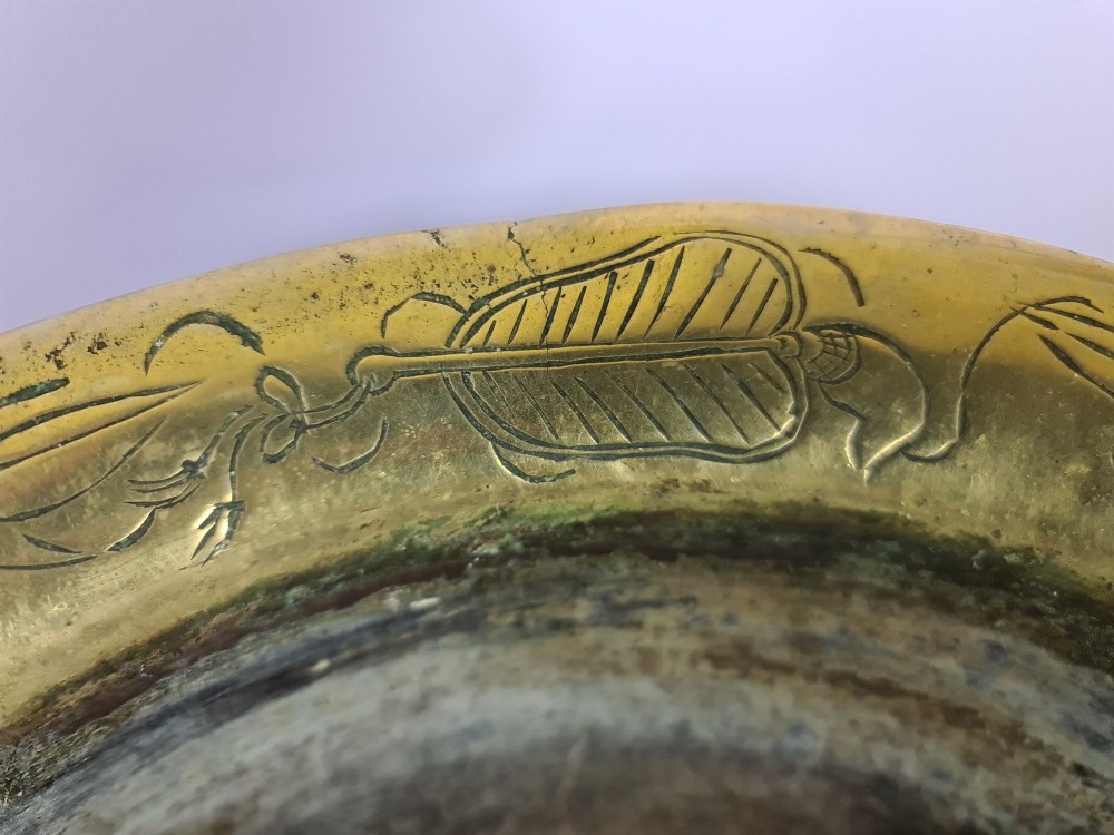 A large brass bowl featuring engraved dragon and cloud patterns with a flared rim, displayed on a dark carved wooden stand. View V