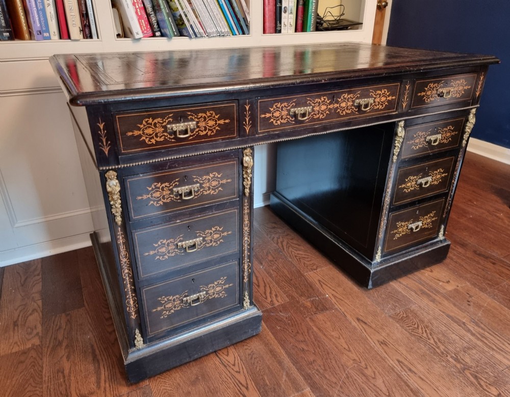 A dark ebonised Victorian pedestal desk featuring detailed floral marquetry inlay, brass handles, ormolu corner mounts, and a leather insert top. View IV