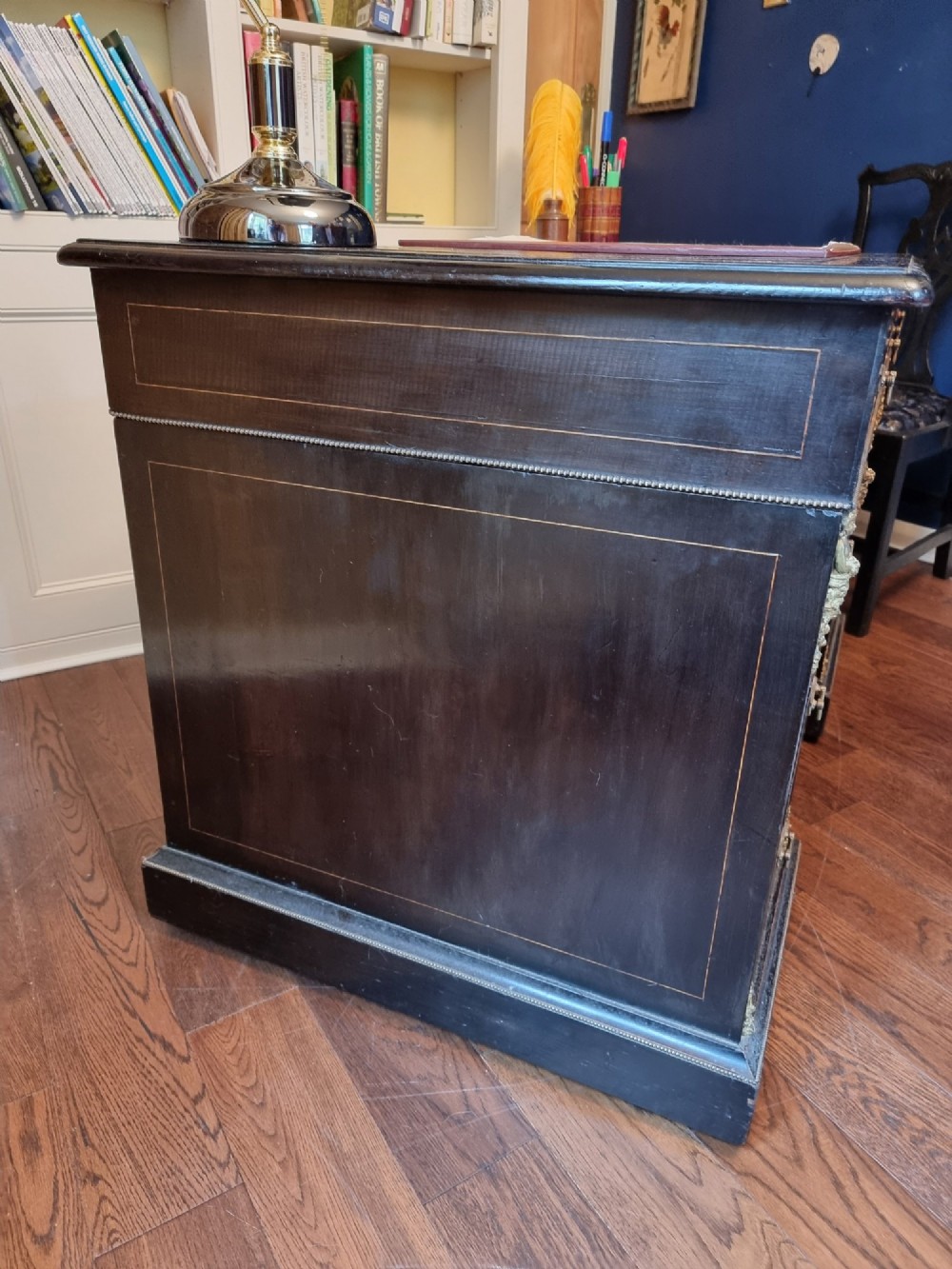 A dark ebonised Victorian pedestal desk featuring detailed floral marquetry inlay, brass handles, ormolu corner mounts, and a leather insert top. View VII