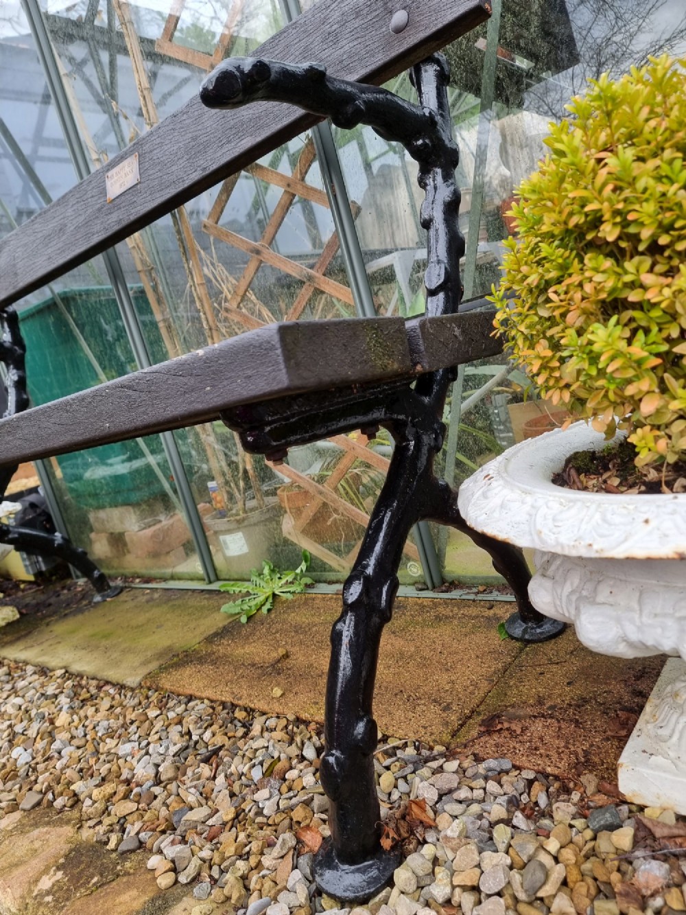A 19th-century style garden bench featuring black cast-iron ends moulded into a branch motif with dark wooden slats forming the seat and backrest. View V